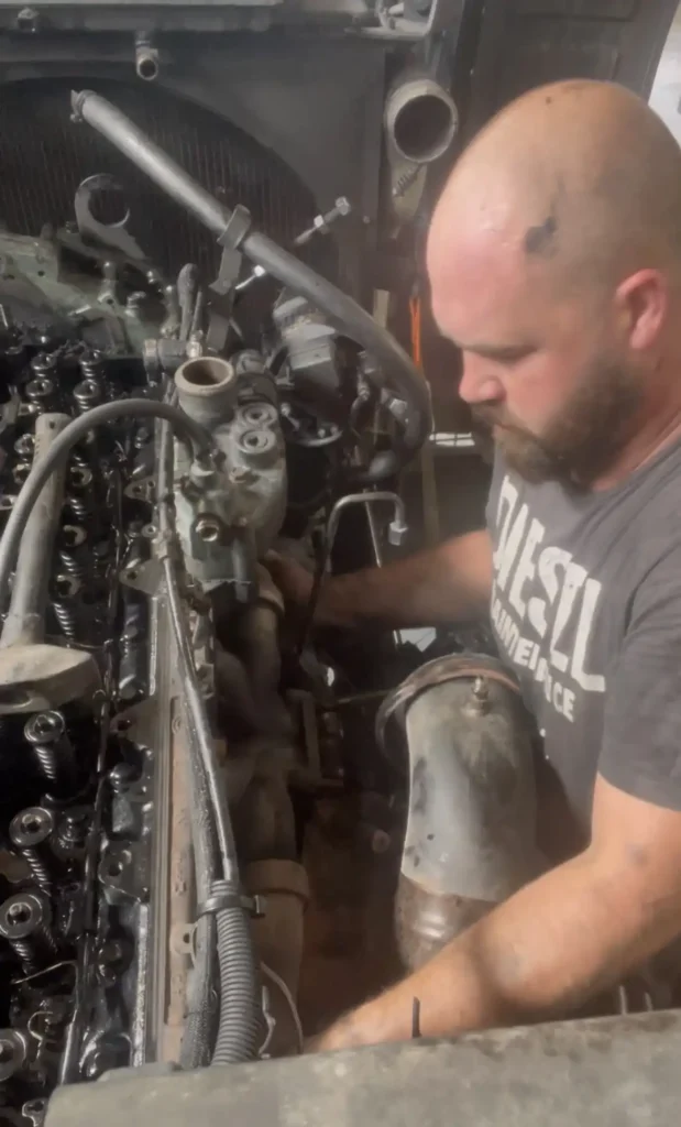 Young bald man with a beard working on a diesel engine.