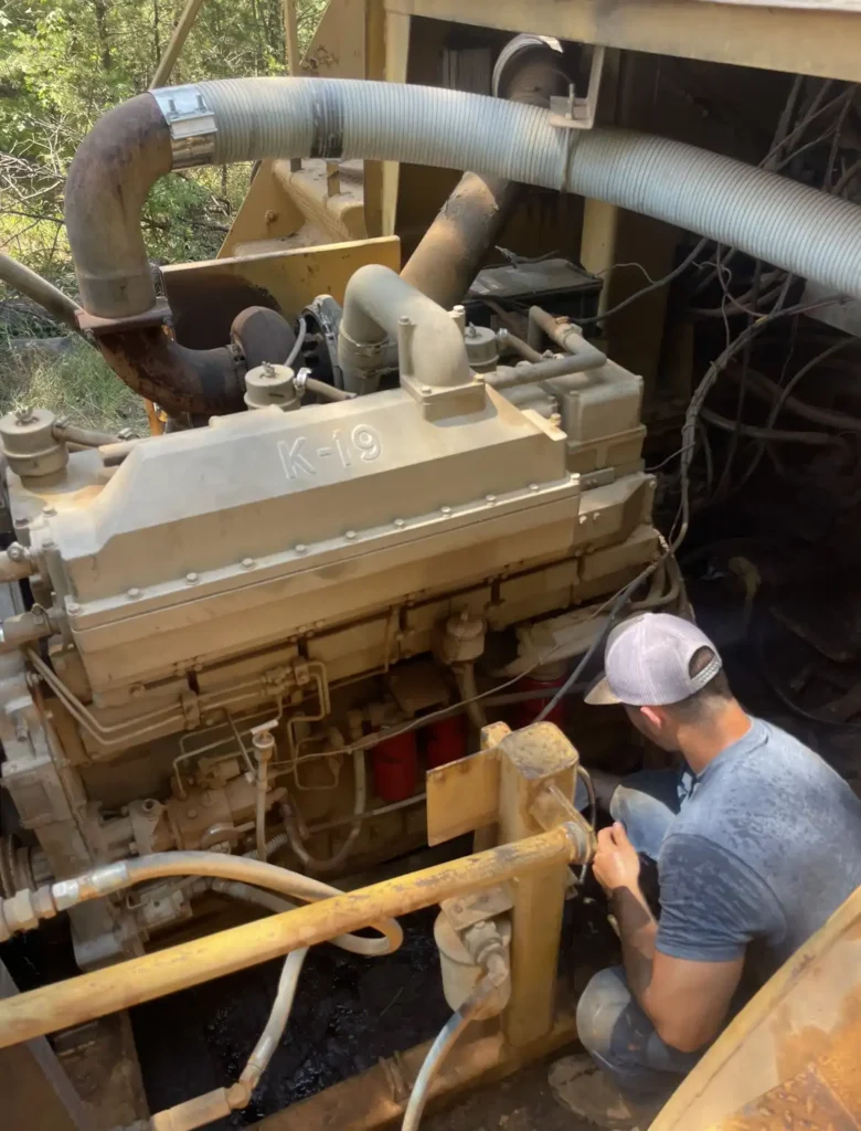 Young man in a hat working on a diesel engine.