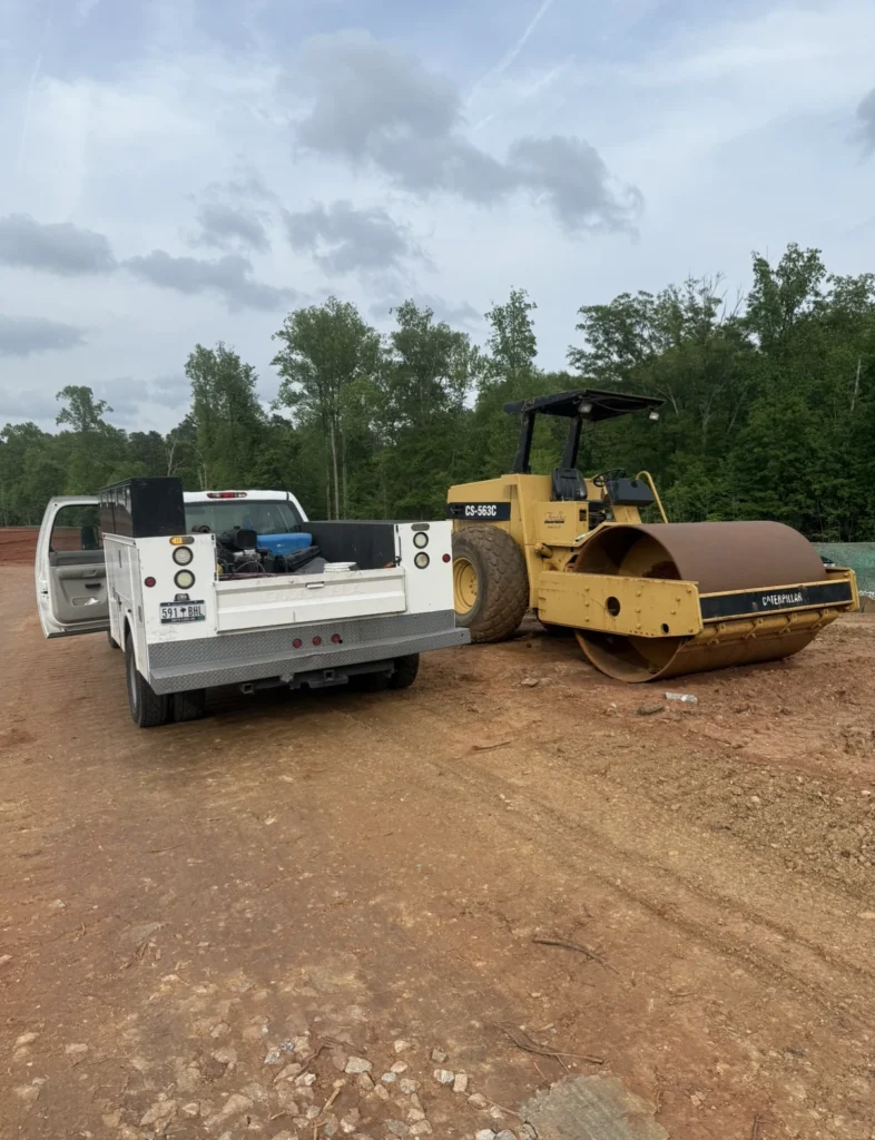 Service truck parked on red dirt next to heavy equipment.